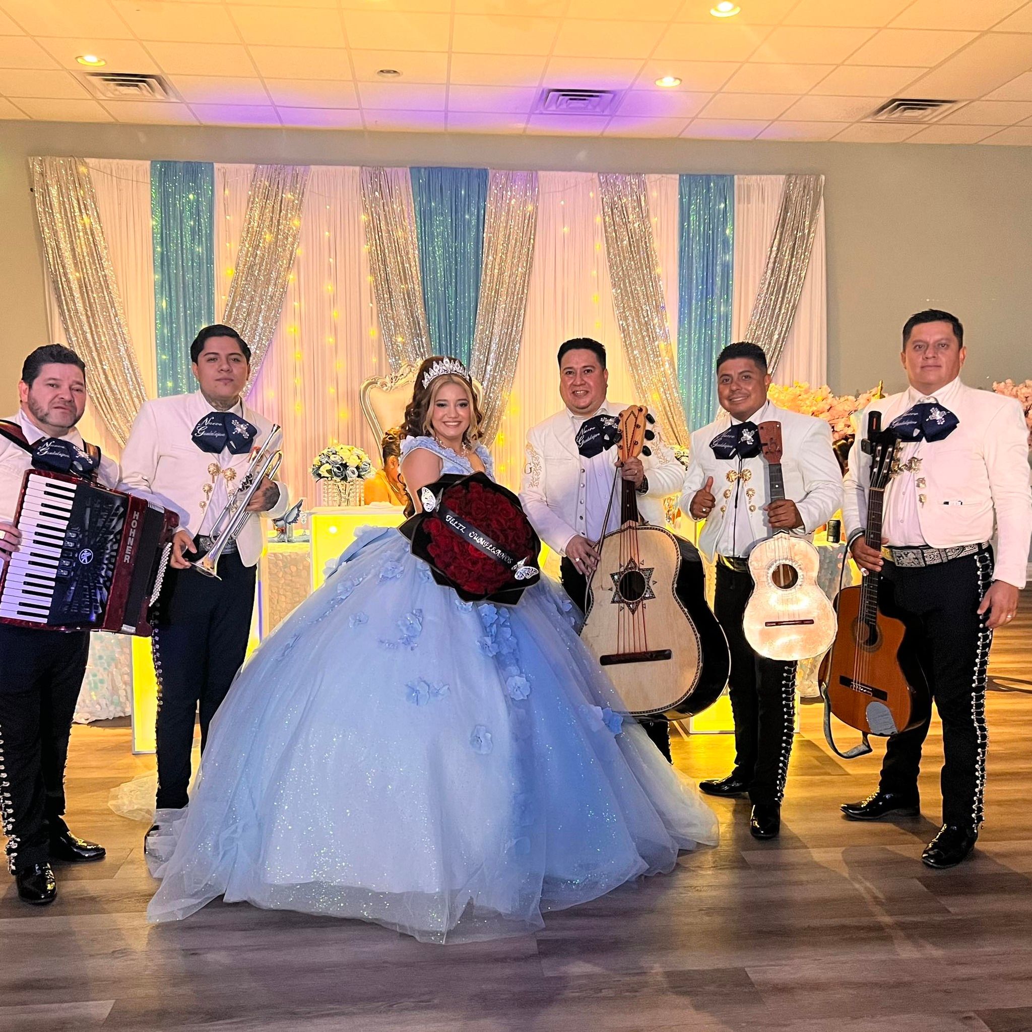 El mariachi posa junto a una quinceañera con vestido azul durante una celebración.